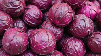 Fresh red cabbage heads are piled together, showing a vibrant purple color and interesting texture