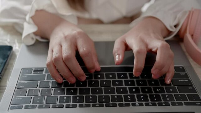 Close-up hand Asian woman sitting working, with hand resting on laptop computer keypad, real fingers typing english letters on keyboard, typing quickly, accurate fluent in just few steps.