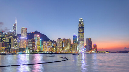 Hong Kong, China skyline panorama with skyscrapers day to night from across Victoria Harbor timelapse.