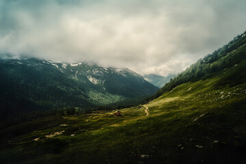 Fototapeta premium Landscape of the Mountains, moody scenic alp mountain photo with low hanging clouds and green meadows