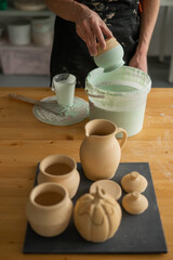 Close-up of a potter's hands glazing a pottery piece. 