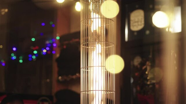 Bright decorative fire burning under a grate, with a shimmering garland in the background. A cozy and festive atmosphere, perfect for holiday settings, celebrations, and winter decorations