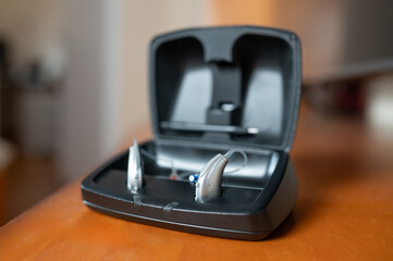 Hearing aid devices charging in open black case on table