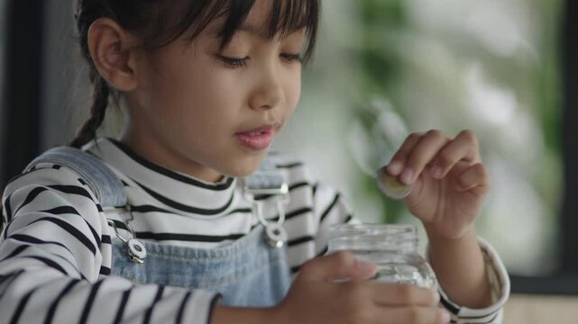 A girl is counting money, saving money, and putting it in a piggy bank.
