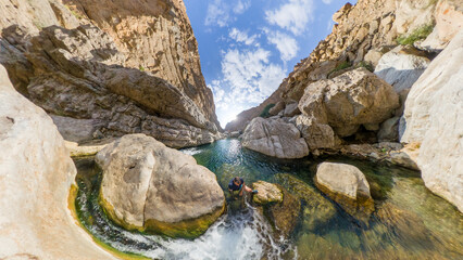 Photo of Wadi Hawer from above, Oman. Man climbs in the rocks of the waters.