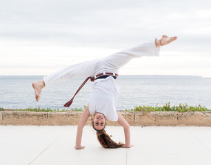 Woman Performing a capoeira Handstand Outdoors Near the ocean