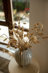 still life. round beige vase with light spikelets.