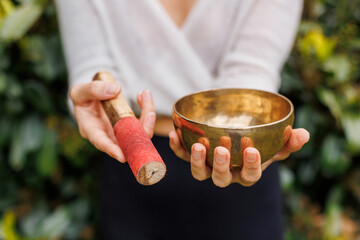 Close-up of a Tibetan singing bowl, held delicately with a red-tipped striker. Common in sound...