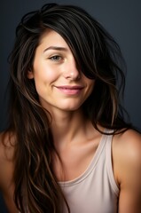 Fototapeta premium Portrait of a Smiling Young Woman with Long Hair Against a Dark Background