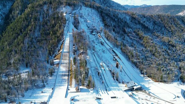 Planica Nordic Centre, nestled in the breathtaking Julian Alps of Slovenia, is a world-renowned destination for ski jumping and winter sports captured from a drone