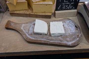 Two pieces of feta cheese lie on a wooden board in the cheese section.
