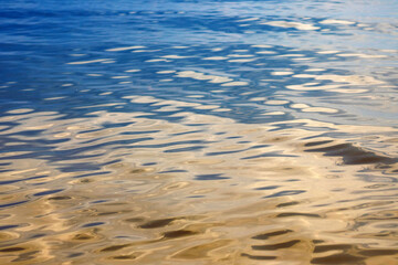 Abstract background of the water surface in the reflections of the golden rays of the sun. Reflection of light.Ripples and waves