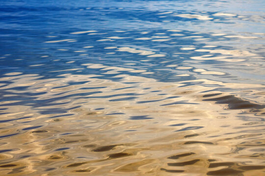 Abstract background of the water surface in the reflections of the golden rays of the sun. Reflection of light.Ripples and waves