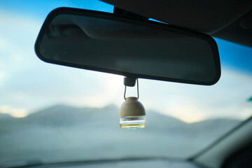 Car air freshener hanging from rearview mirror, mountains in background