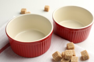 Ceramic casseroles and sugar cubes on white table, closeup