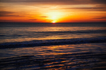 Fototapeta premium Gentle waves rolling onto the shore during a breathtaking golden sunrise over the ocean; Rota, Cadiz, Spain