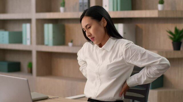 Tired sick Asian business woman Japanese Chinese girl female businesswoman unhealthy Korean overworked worker lady suffering back pain computer laptop sitting work massaging painful backache in office