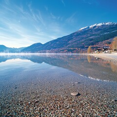 Serene lake view with clear water, mountains, and autumn foliage reflections.