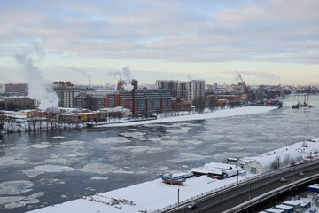 A scenic winter view of an industrial waterfront with a frozen river running through