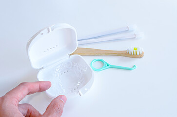 Dedos agarrando placas alineadoras dentales del estuche. Cepillo dental biodegradable, gancho...