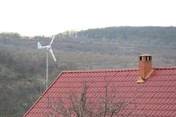A picturesque rural landscape featuring a wind turbine alongside a charming redroofed house