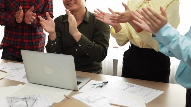 Architect and safety engineer celebrate success design building blueprint project on laptop with architectural document and measurement tool scatter around at modern office. Closeup. Delineation.