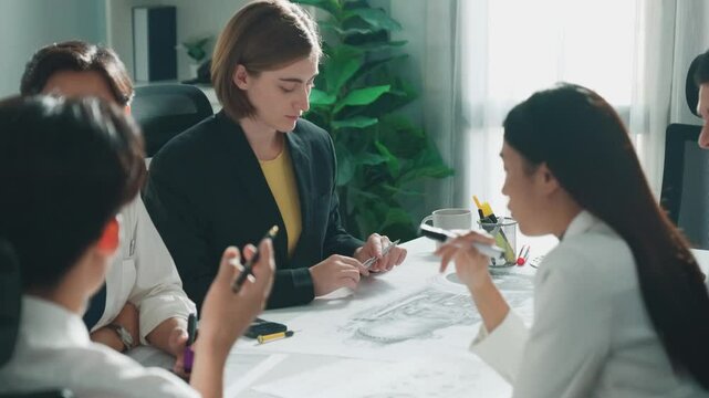 Business woman working and discussing about house model while businessman handed document about architectural model to investor sitting at meeting table with blueprint scattering around. Alimentation.