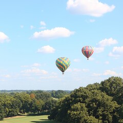 Obraz premium Two colorful hot air balloons floating in a clear blue sky over greenery.