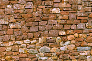 Background of various size and colour old stones creating a wall