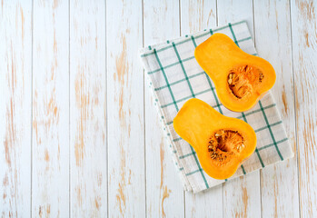 two halves of butternut squash on a light wooden table, copy space for text. Top view.