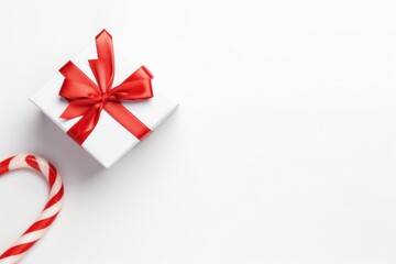 White Gift Box with Red Ribbon and Candy Cane on a Bright Background, Perfect for Holiday Celebrations and Seasonal Decorations