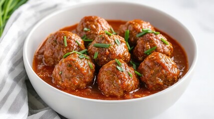 Homemade meatballs simmered in rich tomato sauce served in a white bowl on a marble surface