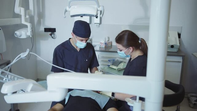Dentists and assistants in medical masks hold a dental instrument that treats teeth patients. Hydience and healthy. Modern clinic