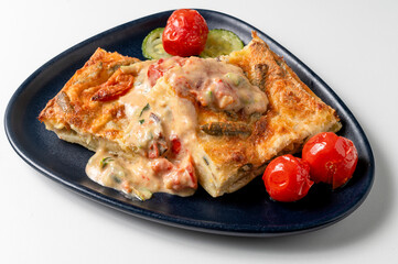 A piece of Italian cheese lasagna with vegetables: green beans , zucchini, peppers and tomatoes isolated in a black dish , delicious traditional Italian dish.