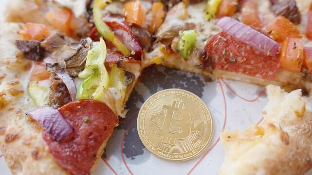 Golden Bitcoin Coin Placed on a Tray Next to a Partially Eaten Pizza with Vegetables and Pepperoni from Close-Up Perspective. Concept of Digital Currency and Food Purchase.