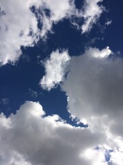 The sky is blue with a few clouds scattered throughout. The clouds are white and fluffy, and they are spread out across the sky. Scene is calm and peaceful, as the clouds are not too dense