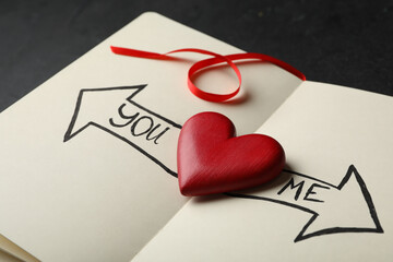 Heart between arrows with words YOU and ME pointing in different directions on notepad. Composition...