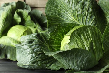 Obraz premium Ripe cabbages on black wooden table, closeup