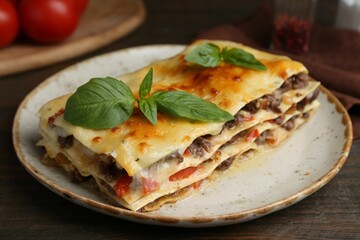 Delicious cooked lasagna with basil on wooden table, closeup