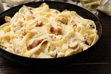 Tasty Alfredo pasta with chicken on wooden table, closeup