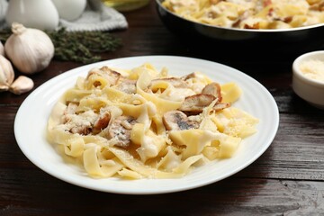 Tasty Alfredo pasta with chicken and mushrooms on wooden table, closeup