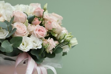 Bouquet of beautiful flowers and eucalyptus branches on green background, closeup. Space for text