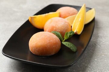 Tasty mochi, cut orange and mint on grey textured table, closeup