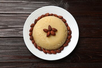 Delicious semolina halva with almonds on wooden table, top view