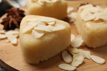 Pieces of delicious sweet semolina halva with almond flakes on wooden board, closeup
