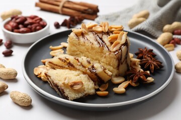 Delicious sweet semolina halva with peanuts and spices on white table, closeup