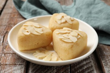 Pieces of delicious sweet semolina halva with almond flakes on wooden table, closeup