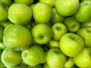 Heap of green apples as background, texture. Healthy eating. Full frame of green apples. Fresh apples from the market. Group of picked raw apples, top view.