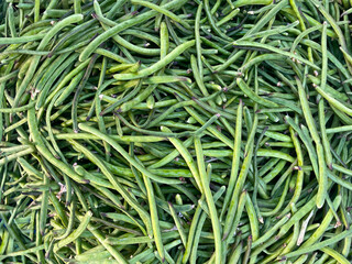 Green beans vegetable, top view background. Large amount of green beans in pods on market stall. Fresh green beans at farmers market in Greece. Healthy, vegetarian food.
