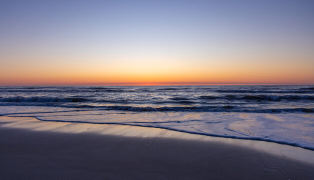 Gentle waves lap up on the shore of the Outer Banks at dawn